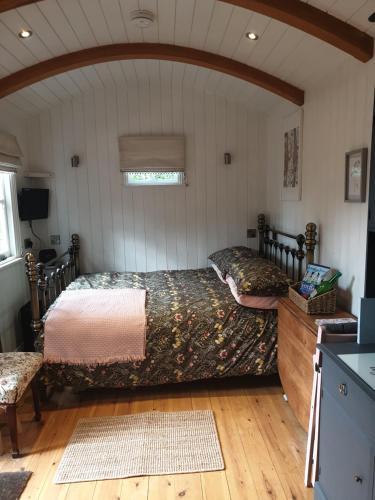 a bedroom with a bed in a room with a window at The Honeypot Shepherds Hut in Ross on Wye