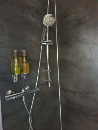 a shower head with two cups on a wall at The Honeypot Shepherds Hut in Ross on Wye