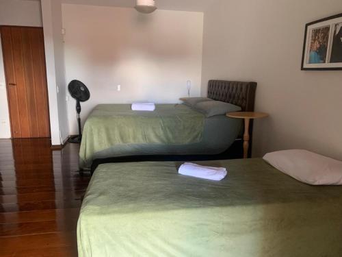 een kamer met 2 bedden en een tafel en een lamp bij Quarto em casa c/piscina in Ouro Fino