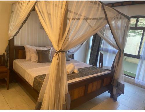 a bedroom with a canopy bed with curtains at Owen Studio in Diani Beach