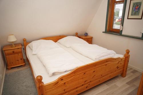 a bedroom with a wooden bed with white sheets at Ferienhaus mit viel Platz in Strandnaehe in Damp