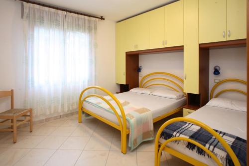 a bedroom with two beds and a chair at Villa Medea in Rosolina Mare