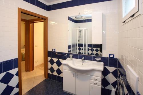 La salle de bains est pourvue d'un lavabo et de carrelage bleu et blanc. dans l'établissement Villa Medea, à Rosolina Mare