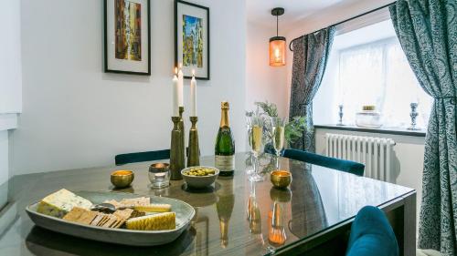 a table with a plate of cheese and wine bottles at Bwthyn Bryn Gwyn in Beaumaris
