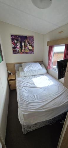 ein kleines Schlafzimmer mit einem weißen Bett und einem Fenster in der Unterkunft the poplars lyons robin hood in Meliden