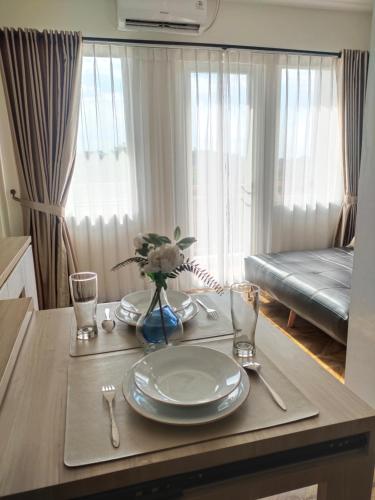 a table with a plate and a vase of flowers on it at Sentul Tower Apartment in Kedungmanggu