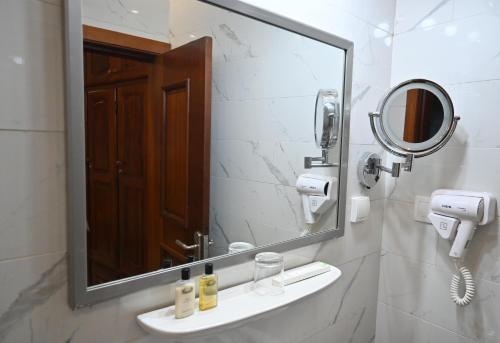 a bathroom with a mirror and a sink at GRAND Hôtel Akwa in Douala