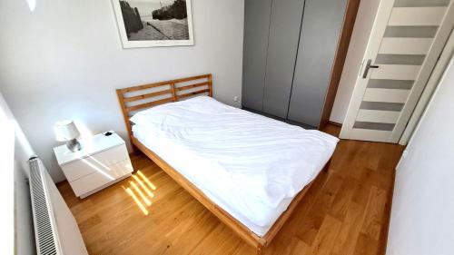 a small bedroom with a bed with white sheets at Bianco Apartament Reduta Park Free Parking in Kraków