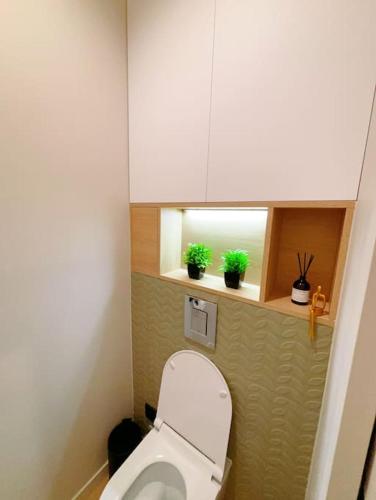 La salle de bains est pourvue de toilettes, d'une fenêtre et de plantes en pot. dans l'établissement Appart close to Eiffel Tower, à Paris