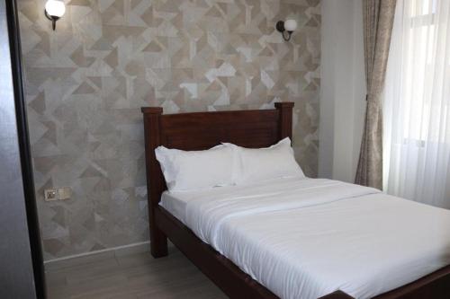 a bedroom with a white bed with a wall at 3 bedroom ensuite apartment Lavington in Nairobi