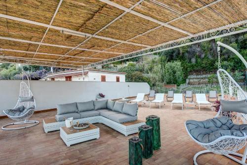 a patio with chairs and a couch and swings at Rooftop Nerano - Amazing Sea View in Nerano