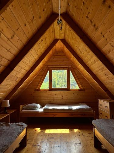a bedroom with a window in a wooden attic at Domki u Oli Kudowa-Zdrój - Balia & Góry Stołowe in Kudowa-Zdrój