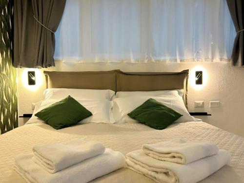 een wit bed met groene kussens en handdoeken erop bij SaliS28 MM3 Affori Centro in Milaan