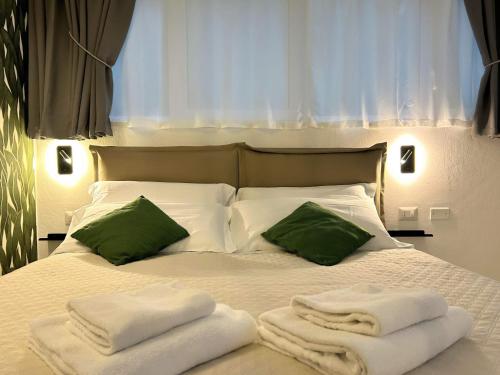 ein weißes Bett mit grünen Kissen und Handtüchern darauf in der Unterkunft SaliS28 MM3 Affori Centro in Mailand