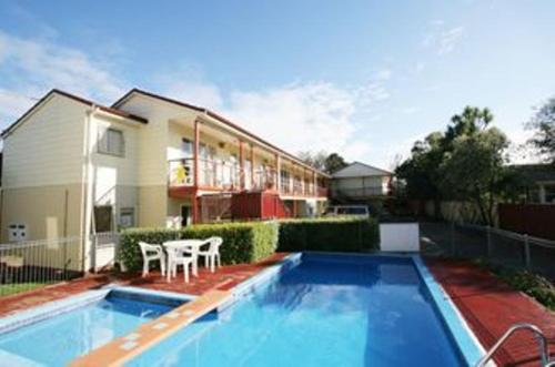 a house with a swimming pool in front of a house at Avondale Motor Inn in Auckland