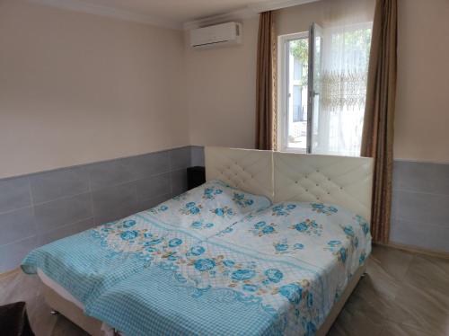 a bedroom with a bed with a blue comforter and a window at Guest House Koba in Batumi