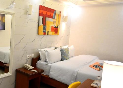 a hotel room with a bed and a mirror at GRAND Hôtel Akwa in Douala