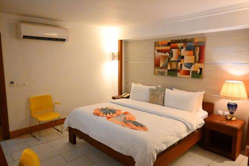 une chambre d'hôtel avec un lit et une chaise jaune dans l'établissement ADAMAOUA GRAND HOTEL AKWA, à Douala