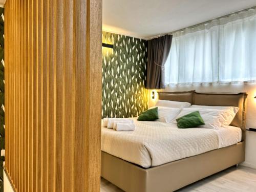 een slaapkamer met een bed met witte lakens en groene kussens bij SaliS28 MM3 Affori Centro in Milaan