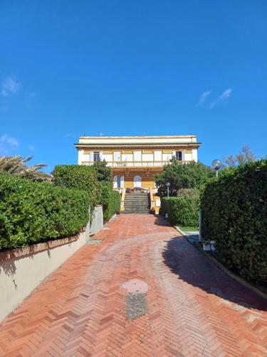 a house with a red brick road in front of a building at Sea-front loft in Liberty villa in Castiglioncello