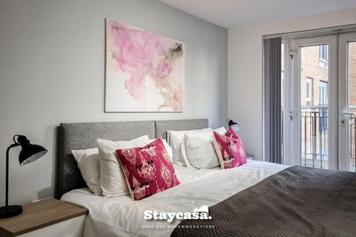 um quarto com uma cama grande e almofadas cor-de-rosa em 2bdr Super King Suite em Manchester