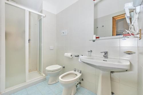 a white bathroom with a toilet and a sink at Hotel Astoria - 3stelle S in Malcesine