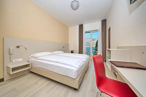 a bedroom with a bed and a desk and a red chair at Hotel Astoria - 3stelle S in Malcesine