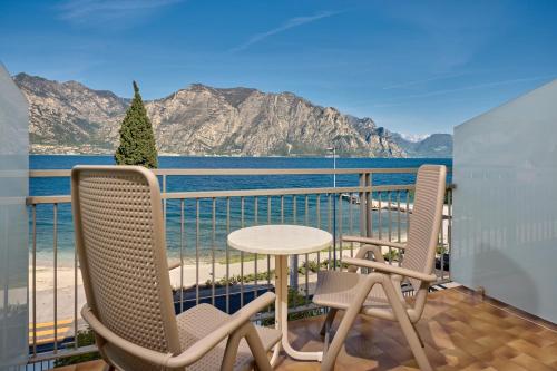 a balcony with two chairs and a table and a view of the water at Hotel Astoria - 3stelle S in Malcesine