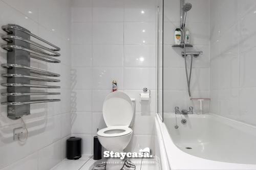 a white bathroom with a toilet and a bath tub at 2bdr Super King Suite in Manchester