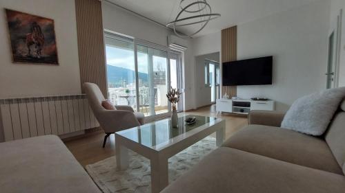 a living room with a couch and a table and a tv at MINA modern & cozy apartment main city square GTC Skopje in Skopje