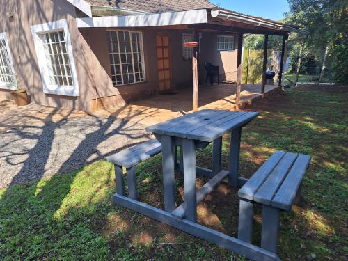 a picnic table and bench in front of a house at Siesta Cottage in Howick