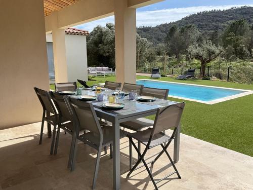 - une table à manger et des chaises sur une terrasse avec piscine dans l'établissement Clemaflo, au Plan-de-la-Tour