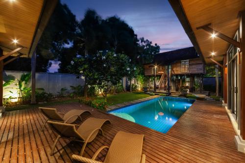 a backyard with a swimming pool with chairs and a house at Saiyuan Estate by TropicLook in Rawai Beach