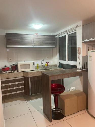 a kitchen with a counter and a red stool in it at ISRAEL TAMBAÚ- Apto Luxuoso- Em frente ao Mar com Varanda in João Pessoa
