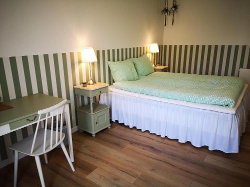 Dormitorio pequeño con cama, mesa y silla en Pension Skovly en Tranekær