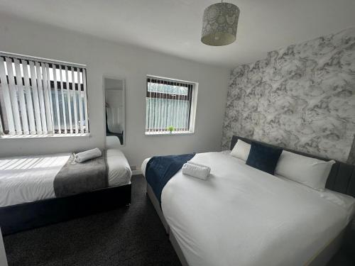 um quarto com 2 camas e 2 janelas em Charming 2-BR Property - Sleeps 5 em Warrington