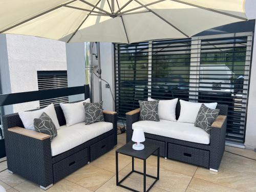 a patio with two chairs and an umbrella at Poolhaus Bodensee ideal für Geschäftsreisende in Wasserburg am Bodensee