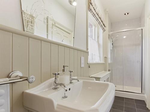 uma casa de banho branca com um lavatório e um espelho em Housekeepers Cottage - Uk47216 em Great Bolas