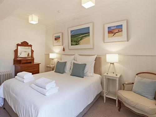 um quarto com uma cama branca e uma cadeira em Housekeepers Cottage - Uk47216 em Great Bolas