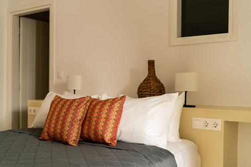 a bedroom with a bed with pillows and a vase on the wall at Tagoo Studios Mykonos in Mýkonos City