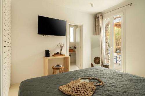 a bedroom with a bed with a television on the wall at Tagoo Studios Mykonos in Mýkonos City