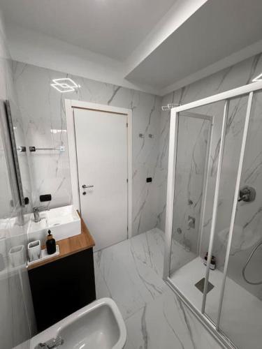 a white bathroom with a shower and a sink at Andrea’s Lake View House - Bellagio in Civenna