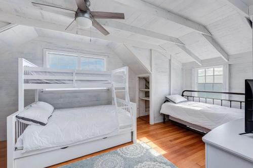 2 łóżka piętrowe w białym pokoju z wentylatorem sufitowym w obiekcie 6.5-Acre Oceanfront Estate w mieście Wakefield