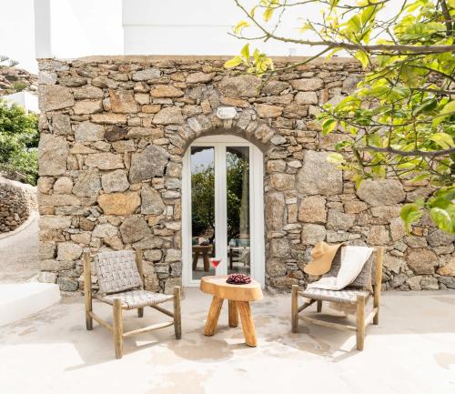 a stone house with two chairs and a table at Tagoo Studios Mykonos in Mýkonos City