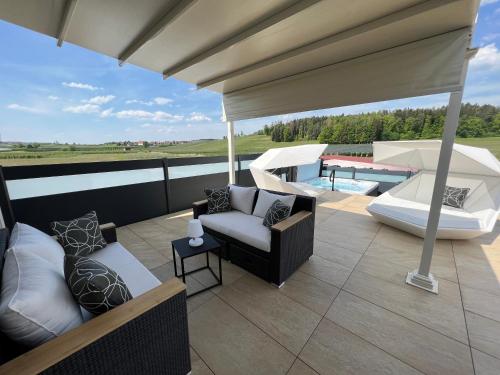 a patio with a couch and chairs on a roof at Poolhaus Bodensee ideal für Geschäftsreisende in Wasserburg am Bodensee