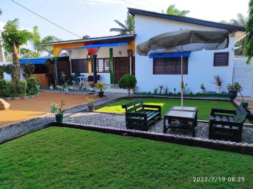 ein Haus mit einem Hof mit Bänken und einem Regenschirm in der Unterkunft Résidence GreenArt Mamert et services in Porto-Novo