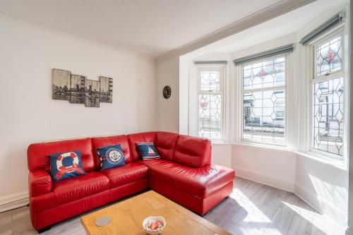 um sofá de couro vermelho numa sala de estar com janelas em I know you'll love this house 5min walk from beach em Great Yarmouth