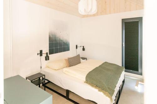 a white bedroom with a bed and a window at Fred I Tiny House op de Veluwe in Epe