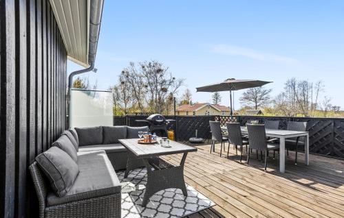 a patio with a couch and tables and an umbrella at Amazing Home In Frederikshavn in Frederikshavn