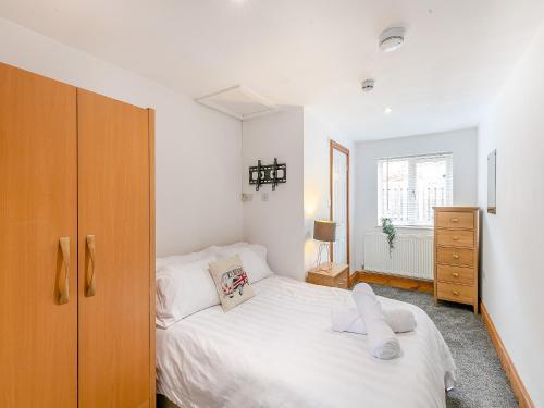 a bedroom with a white bed and a wooden cabinet at The Lodge in Gloucester